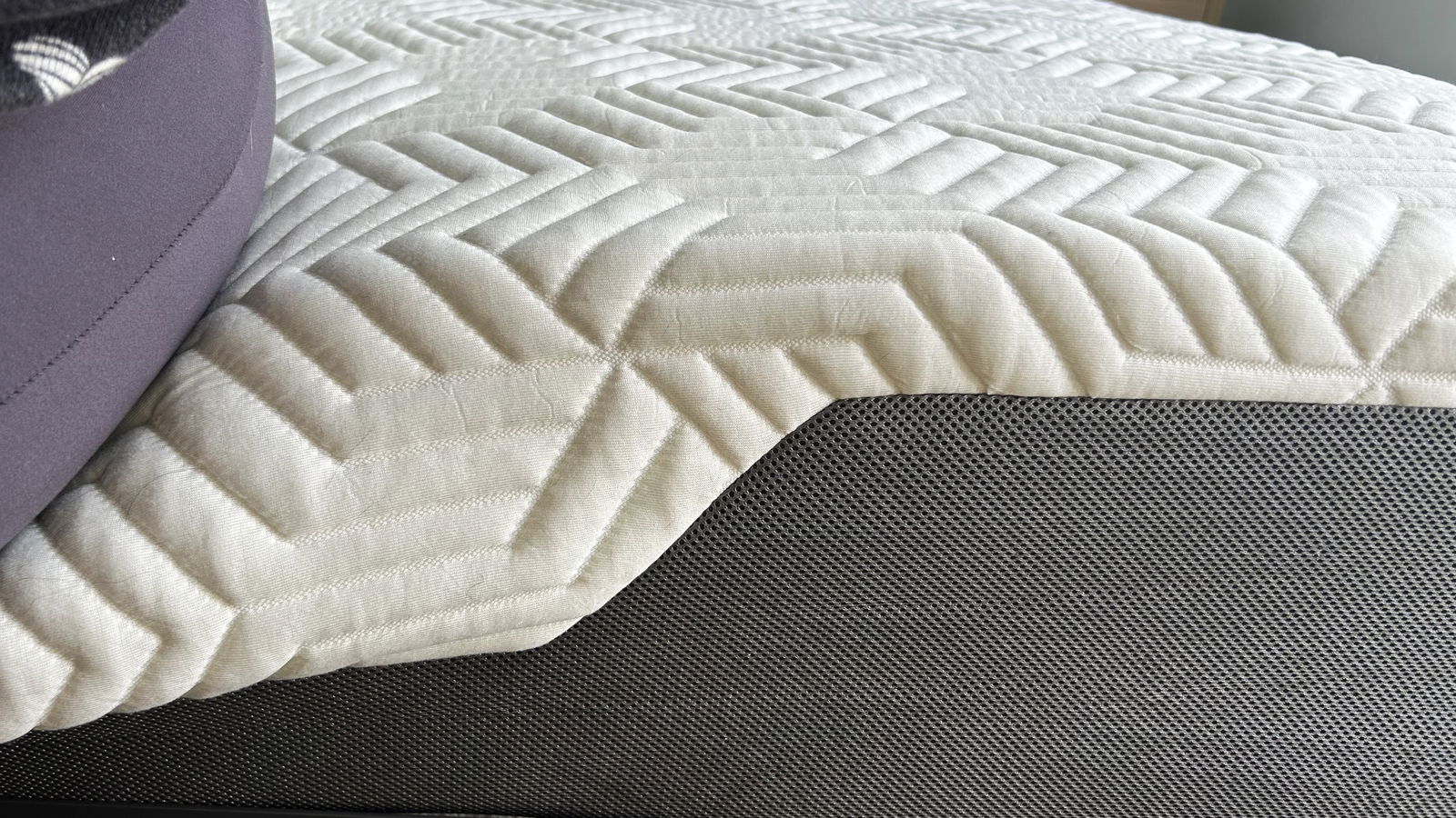 Image depicting compression of Valmori Hybrid II mattress when sat on and shows the white and grey detailing of the mattress edge