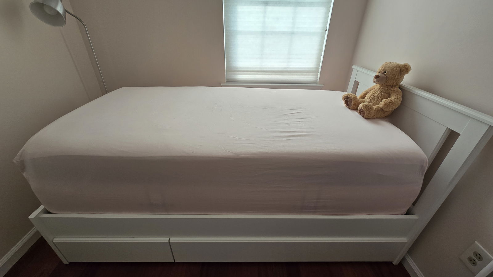 The Tempur-Pedic Tempur-Adapt + Cooling Mattress Topper covered in a mattress cover and a fitted sheet, with a teddy bear on top