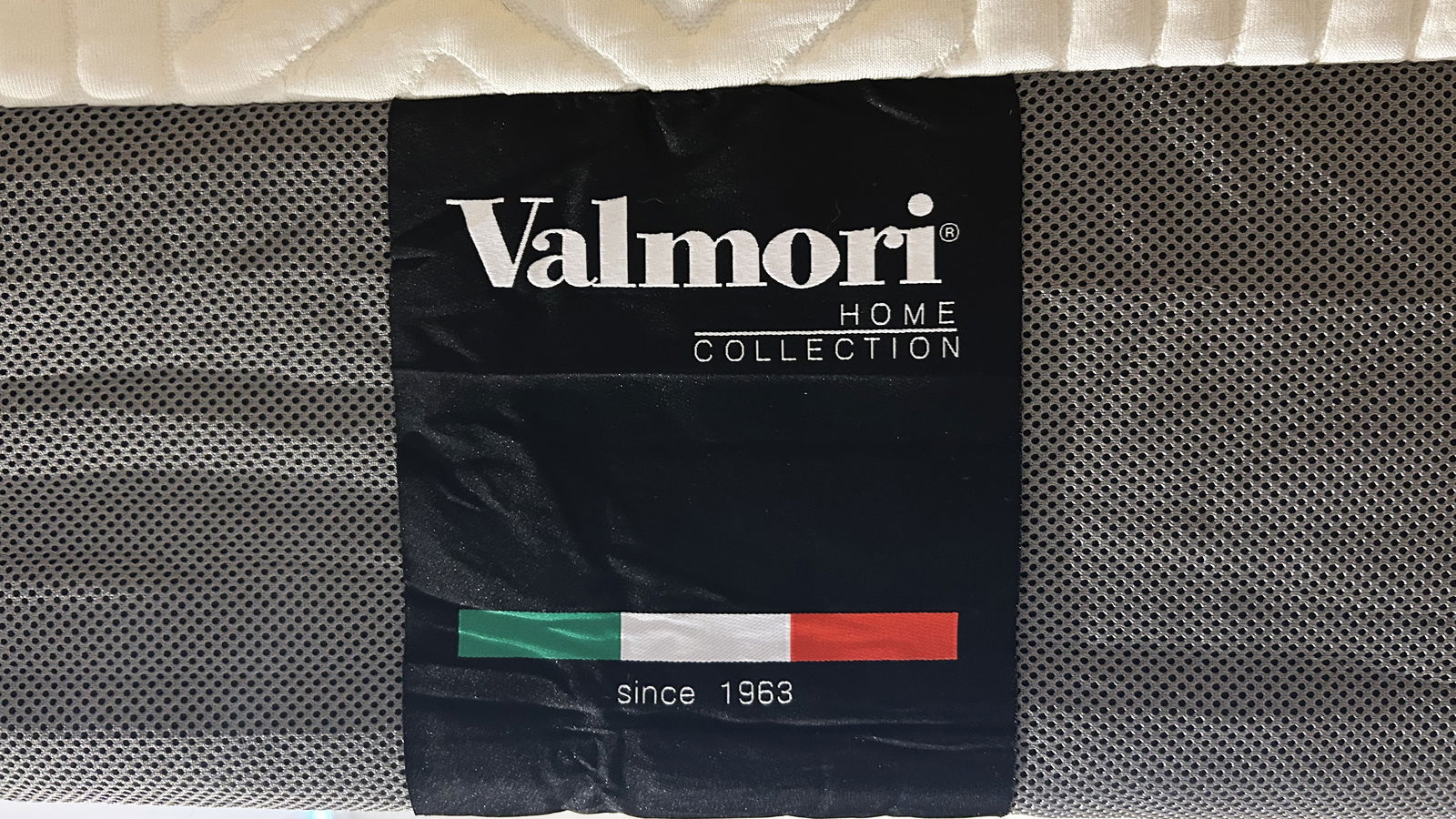 Valmori Hybrid II mattress handle and Valmori logo on black fabric with red, white and green underneath