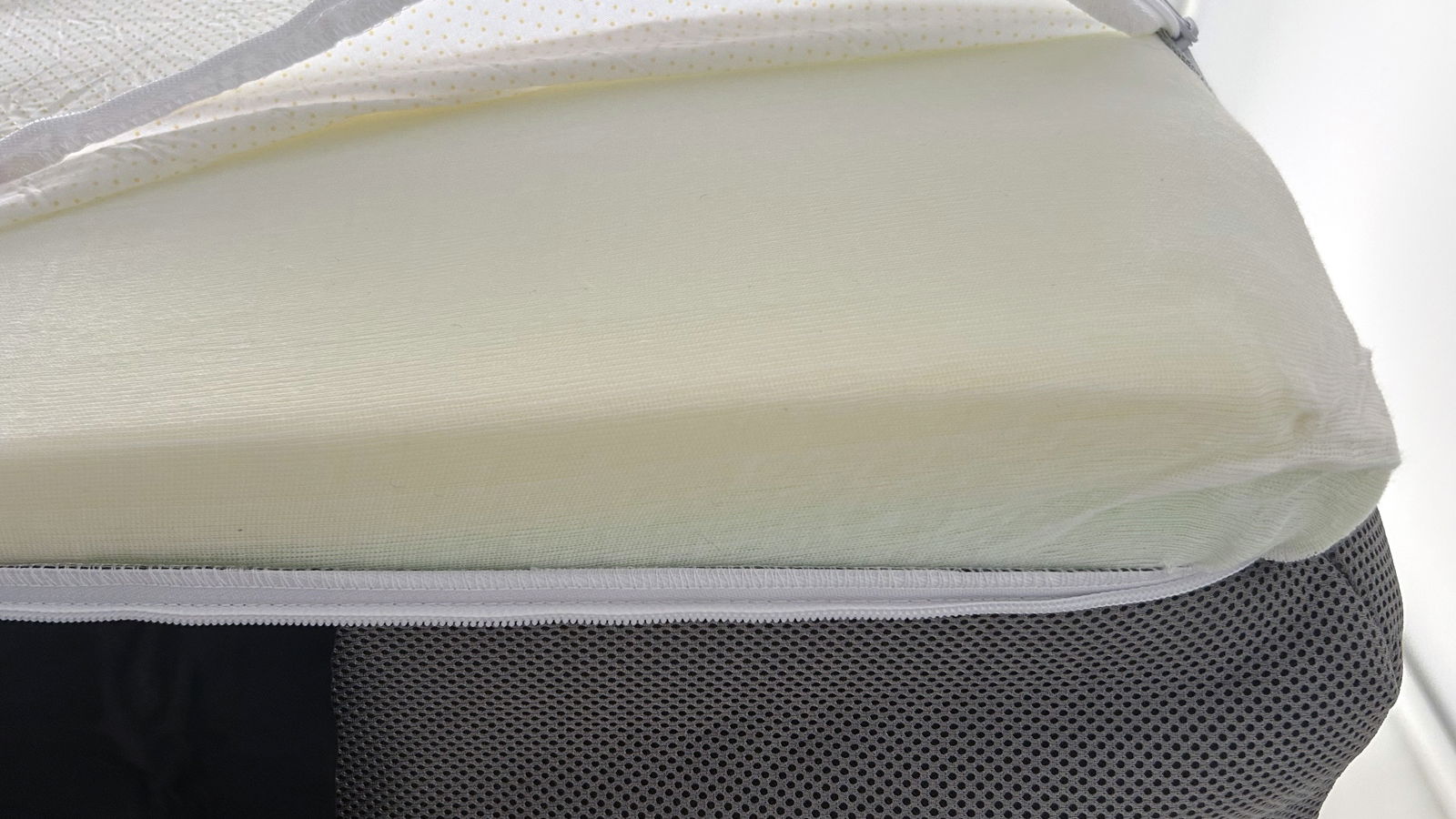 Valmori Hybrid II mattress with cover semi-removed, showing foam topper and light blue stripe of memory foam layer