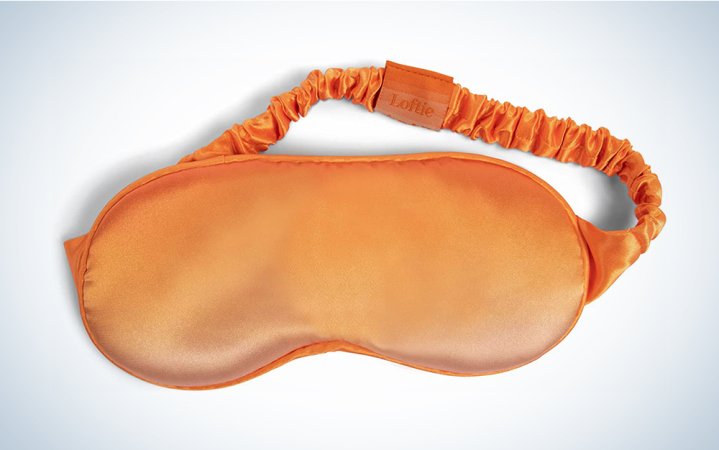  An orange ombre sleep mask from Loftie on a blue and white background