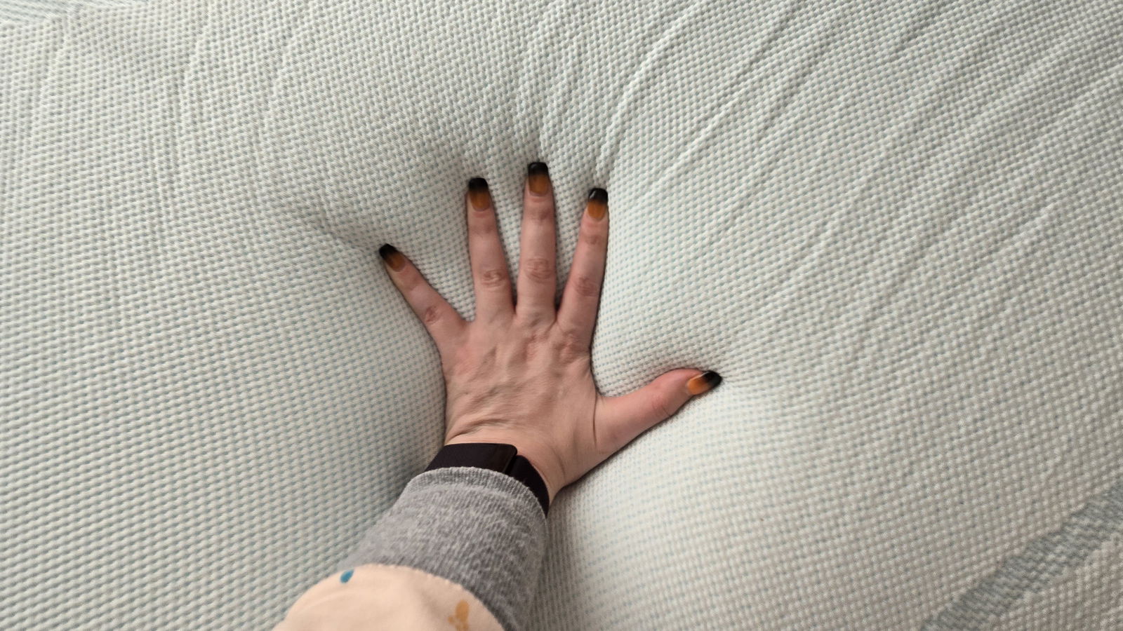 Our tester's hand on the cover of the Tempur-Pedic Tempur-Adapt + Cooling Mattress Topper